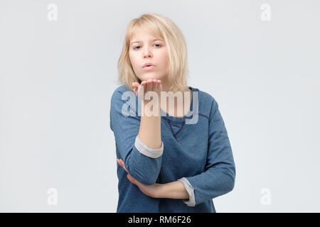 Charming lovely woman with blond hair sending an air kiss Stock Photo