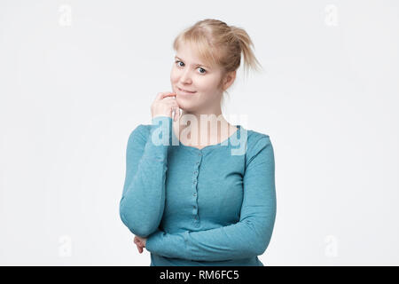 Pretty teenager with blond hair, dressed casually, looking with satisfaction at camera Stock Photo