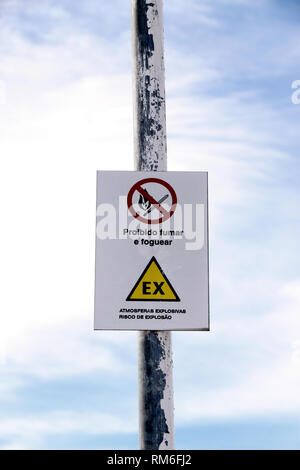 Sign next to a communications center in Portuguese. Translation: The sign above says 'MAKE NO SMOKING AND FIRE'; The sign below says 'EXPLOSIVE ATMOSP Stock Photo