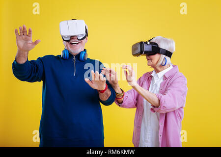 Retired man feeling emotional wearing VR glasses with his wife Stock Photo