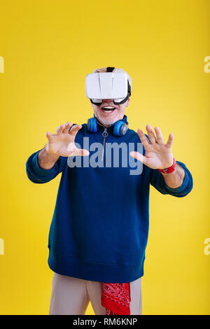Stylish retired man wearing beige trousers wearing VR glasses Stock Photo