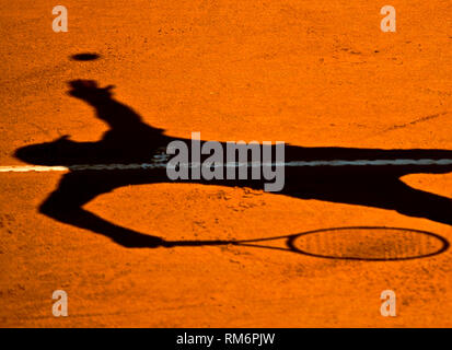 Shadow of a tennis player serving Stock Photo