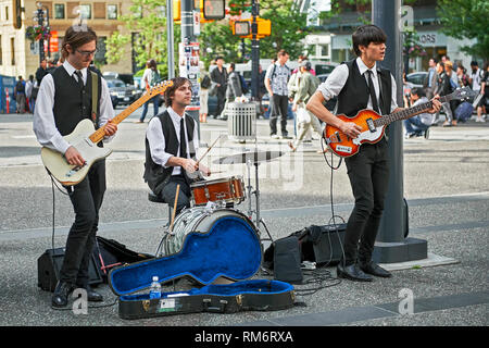 Vancouver, B.C., Canada - June 21, 2012: Three student Beatles revival musicians performing openly in downtown area to improve their budget Stock Photo