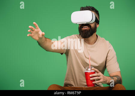 smiling man with soda using Vr headset isolated on green Stock Photo