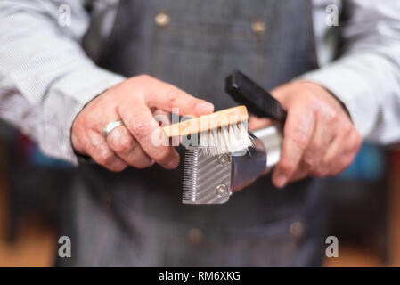 Barber cleaning electric hair clipper at barber shop. Stock Photo