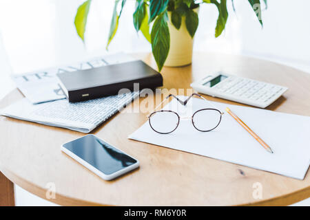 smartphone near glasses and travel newspaper on coffee table Stock Photo
