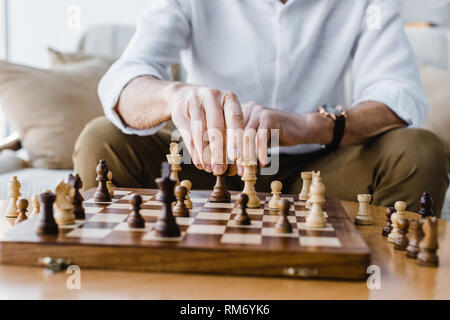 cropped view of retired man with playing chess at home Stock Photo