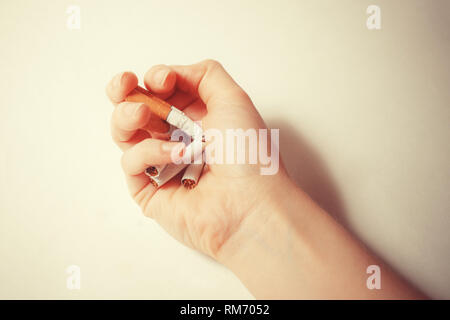 Close-up hand crushing a pile of cigarettes. Angry hand breaking tobacco. Gesture for anti, quit smoking addiction concept. Stop smoking message, soci Stock Photo