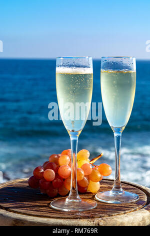 Champagne, prosecco or cava served with pink grape in two glasses on outside terrace with sea view close up Stock Photo