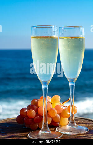 Champagne, prosecco or cava served with pink grape in two glasses on outside terrace with sea view close up Stock Photo