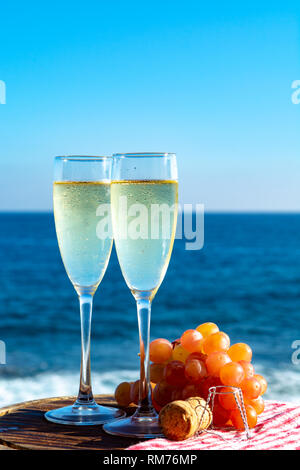 Champagne, prosecco or cava served with pink grape in two glasses on outside terrace with sea view close up Stock Photo