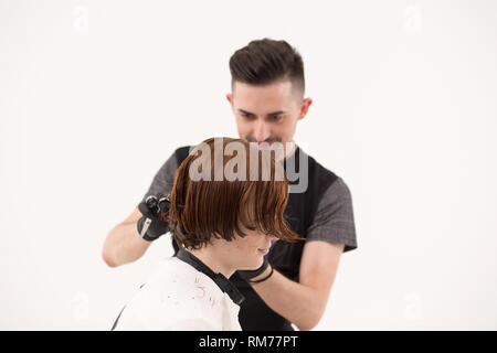 Barber is trimming client's hair with scissors Stock Photo