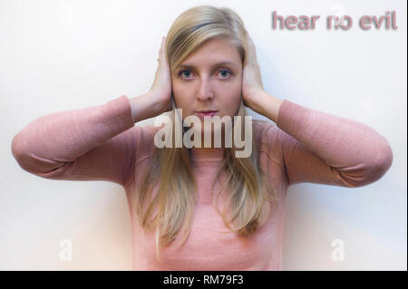 young woman showing the proverbial principle of three wise monkeys - hear no evil Stock Photo