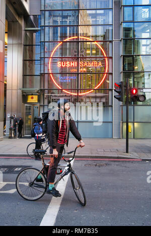 Man balancing his bicycle by standing on pedals waiting for traffic light to change, City of London, London, England, UK Stock Photo