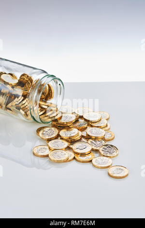 £1 Coins Falling from a Glass Saving Jar Stock Photo