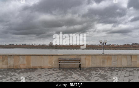 Lonely bench on the river embankment Stock Photo
