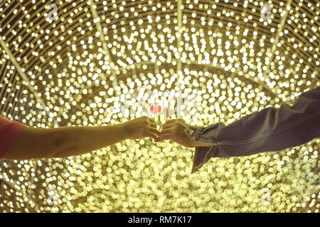 Romantic couple on valentines day. Happy joyful couple give heart candle to each other with decorate colorful light bulbs in garden., Love concept. Stock Photo