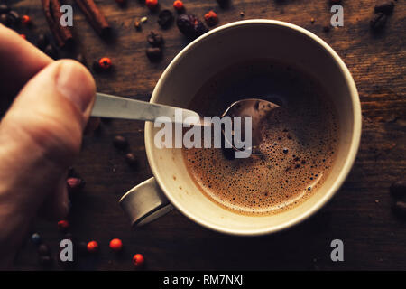 Male hand steering coffee in a cup with spoon, top view Stock Photo