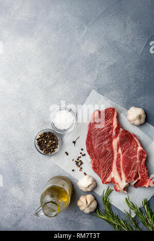 Tasty fresh beef meat with spices like garlic, salt, pepper, herbs at craft paper on gray background. Concept of german food Stock Photo