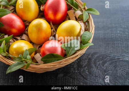 Easter eggs in a wicker basket on a dark wooden background Stock Photo