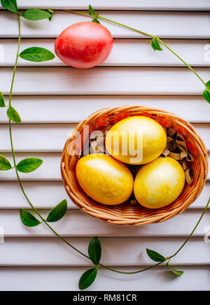 Multi-colored Easter eggs in a wicker basket on a white background. Living coral color. Stock Photo