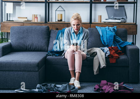 depressed woman sitting with glass of red wine while packing in living room after breaking up with boyfriend Stock Photo