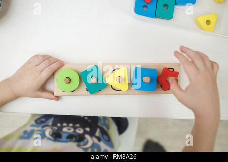 Toddlers playing multicolored educational games, mosaic and puzzles table. Stock Photo