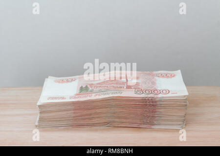 Big stack of Russian money banknotes of five thousand rubles lying on a wooden table Stock Photo