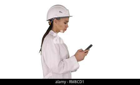 Engineer using mobile phone texting while walking on white background. Stock Photo