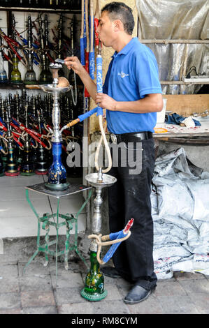 An Shisha bar waiter testing a shisha, an Arabic smoking pipe at a shisha bar before delivering it to a customer in Dubai in the United Emirates, (UAE Stock Photo