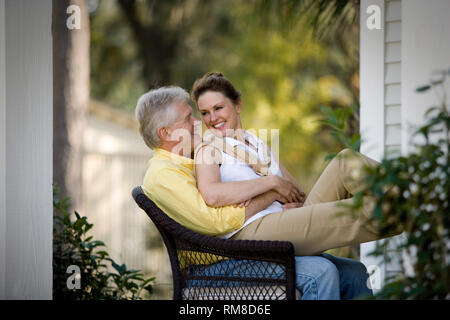 Mature adult woman sitting on her husbands knee. Stock Photo