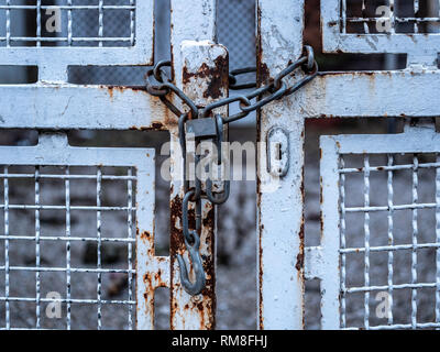 Image of old chain with padlock and white iron gate. close-up Stock Photo