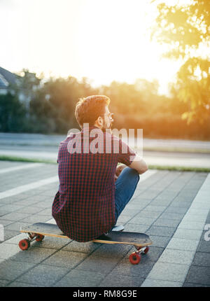 Man sitting on his longboard Stock Photo