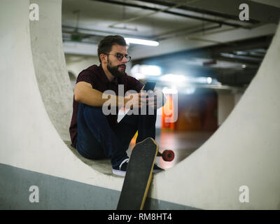 Hipster skater using smart phone in underground Stock Photo