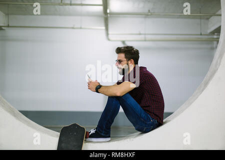 Hipster skater using smart phone in underground Stock Photo