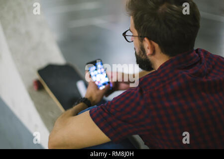 Hipster skater using smart phone in underground Stock Photo