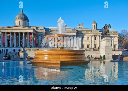 LONDON TRAFALGAR SQUARE THE NATIONAL GALLERY WITH PEOPLE AND A FOUNTAIN IN EARLY MORNING Stock Photo