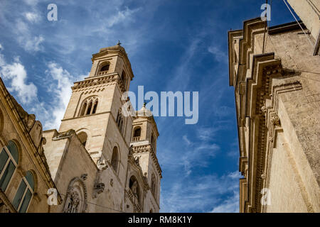 Side street view of the Cathedral of Santa Maria Assunta and its facades and elevations in scenery summer day with blue sky and puffy white clouds. Italy, Puglia region, Altamura Stock Photo