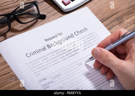 Close-up Of A Person's Hand Filling Criminal Background Check Form With Pen Stock Photo