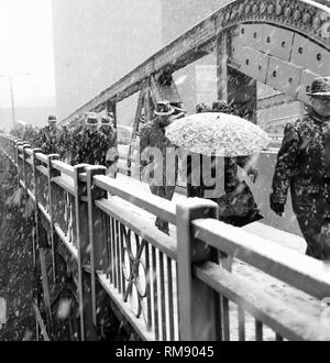 Pedestrians cross the State Street bridge over the Chicago River during a snowstorm,ca 1960. Stock Photo