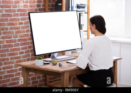Close-up Of A Businesswoman Looking At White Computer Screen Over The Wooden Desk Stock Photo