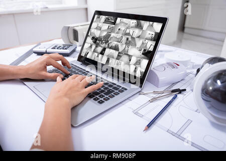Close-up Of A Woman Monitoring Home Security Cameras On Laptop Over The Blue Print Stock Photo