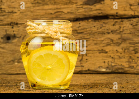 Olive oil flavored with lemon and red beans and black pepper in a glass jar on old wooden background Stock Photo