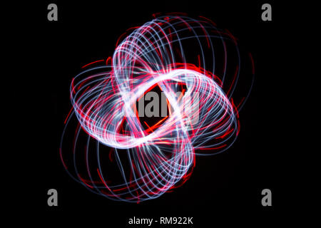 Light painting forming an elliptic shape with blueish continuous white lines and short dashed red lines against a black background. Stock Photo