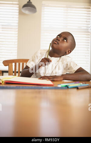 African American boy doing homework on dining table in kitchen Stock Photo