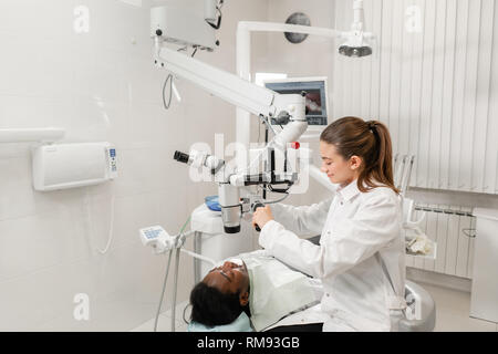 Female dentist advanced user, dental tools. Setup microscope for examining his patients teeth. in dental clinic office. Medicine, dentistry and health Stock Photo