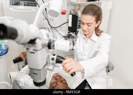 Female dentist advanced user, dental tools. Setup microscope for examining his patients teeth. in dental clinic office. Medicine, dentistry and health Stock Photo