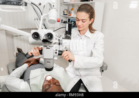 Female dentist advanced user, dental tools. Setup microscope for examining his patients teeth. in dental clinic office. Medicine, dentistry and health Stock Photo
