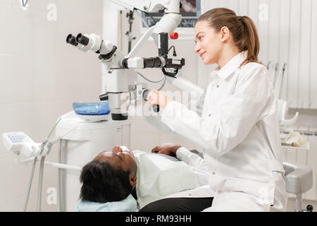 Female dentist advanced user, dental tools. Setup microscope for examining his patients teeth. in dental clinic office. Medicine, dentistry and health Stock Photo