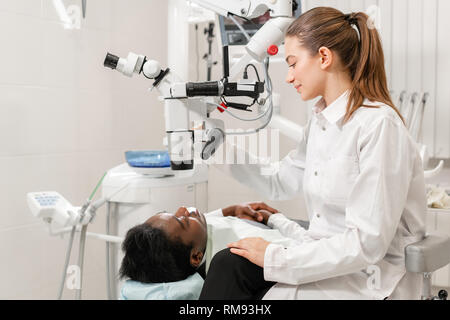 Female dentist advanced user, dental tools. Setup microscope for examining his patients teeth. in dental clinic office. Medicine, dentistry and health Stock Photo